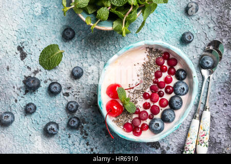 La lumière du yaourt grec ou crème dessert avec chia seeds, Goji Berry frais et servi dans un bol bleu, vue du dessus Banque D'Images