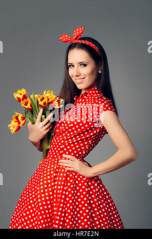 Jolie fille en robe rouge à pois rétro avec des tulipes Banque D'Images