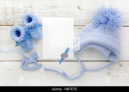 Chaussons pour bébé avec une carte vierge et cap sur un fond de bois blanc Banque D'Images