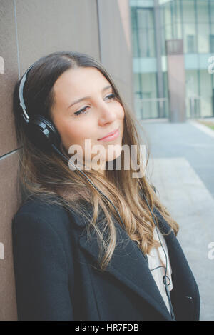 Jeune femme d'affaires authentique se détend en écoutant de la musique dans la ville Banque D'Images