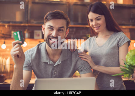 Commande en ligne. Couple dans la commande en ligne de l'alimentation cuisine restaurant. Ils en utilisant l'ordinateur portable. Man looking at camera et souriant tout en payant avec cred Banque D'Images