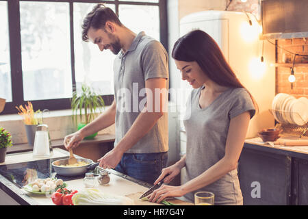 Jeune beau couple dans la cuisine. Famille de deux à préparer les aliments. Couple délicieux plats de pâtes. Beau loft intérieur avec les ampoules et grande fenêtre Banque D'Images