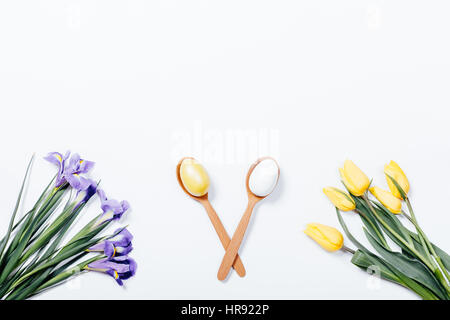 Tulipes jaune, violet iris et deux cuillère à oeufs de Pâques sur un fond blanc, vue du dessus Banque D'Images
