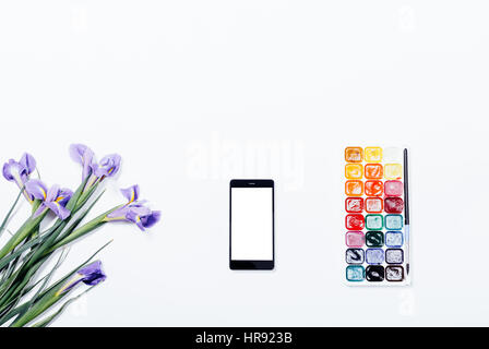 Fleurs violettes, un téléphone mobile et les peintures à l'aquarelle sur un tableau blanc Vue de dessus Banque D'Images