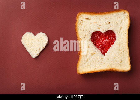 La composition de la Saint-Valentin. Côté gauche : coeur de pain blanc, le côté droit : sandwich avec coeur rouge de la confiture de framboises. Banque D'Images