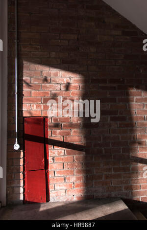 Soleil et ombres sur un vieux mur de brique rouge avec hatch Banque D'Images