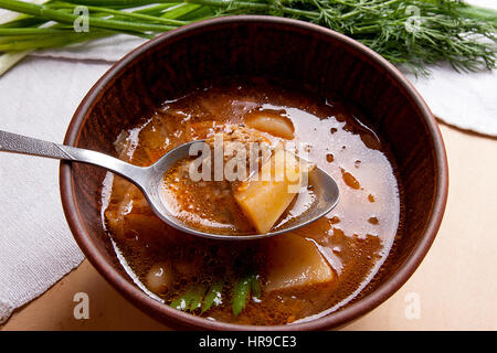 Vue rapprochée de la plaque d'argile et une cuillère à soupe de betteraves rouges ou borsch. Le bortsch ukrainien soupe à la tomate sur fond de bois. Banque D'Images