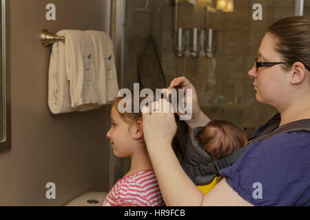 Fixation mère filles cheveux avec bébé attaché sur sa poitrine Banque D'Images