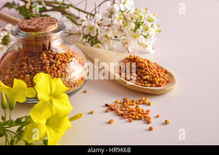 Grains de pollen en pot et cuillère en bois sur la table en bois avec décoration de fleurs. Vue élevée. Composition horizontale Banque D'Images
