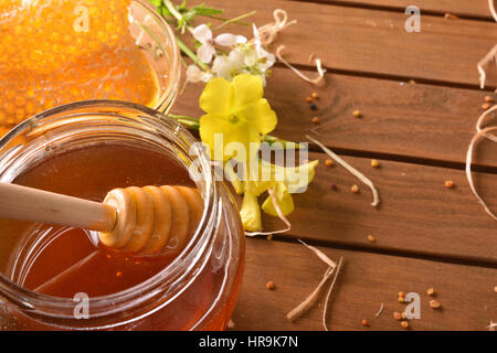 Pot de miel et de miel dans un bol en verre sur une table en bois brun foncé avec des fleurs et du pollen d'abeille. Top View. Composition horizontale Banque D'Images