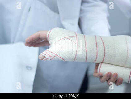 Médecin l'application d'un plâtre et des pansements à l'avant-bras et du poignet du patient afin d'immobiliser une fracture après une blessure. Banque D'Images