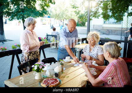 Groupe de hauts fonctionnaires à l'élégant se détendre en été cafe et de cartes à jouer les uns avec les autres Banque D'Images