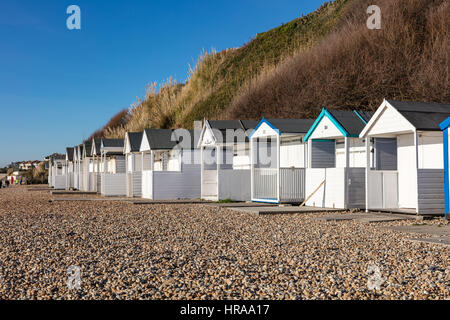 Une rangée de cabanes de plage sous les falaises de Bexhill, sur la plage de galets sous un ciel bleu, Bexhill on Sea, East Sussex, UK Banque D'Images