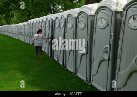 Une dame entrant dans une partie d'une très longue rangée de toilettes portables dans le Parc LaFontaine à Montréal pendant la Marathon de Montréal Banque D'Images