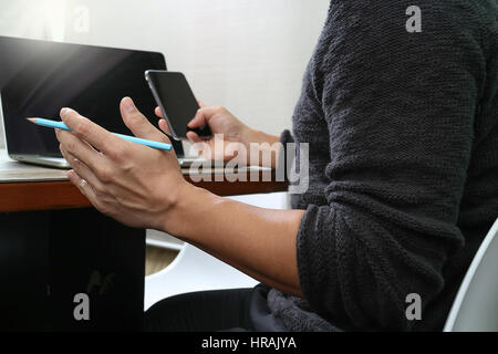 Designer la main à l'aide de paiements mobiles,vente en ligne omni channel,ordinateur portable sur un bureau en bois in modern office Banque D'Images