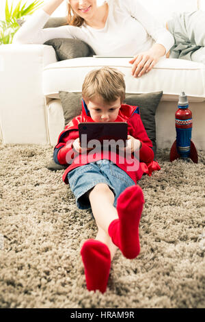 Petit garçon super-héros les jeux vidéo et la mère couchée sur le canapé dans le salon. Banque D'Images