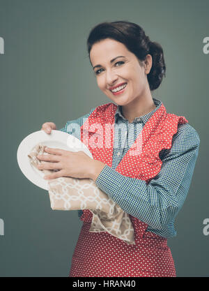 Smiling vintage femme de séchage et polissage d'un plat avec un chiffon Banque D'Images