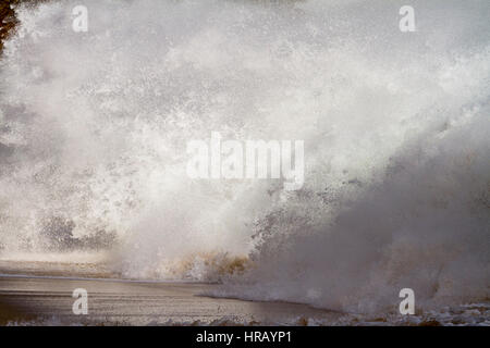 Cornwall, UK. 28 Février, 2017. Météo britannique. Une recherche de sensations fortes se surfer engloutie par une vague géante en essayant d'entrer dans l'eau pour surfer les vagues générées par la tempête Ewan. Les vagues massives jusqu'à vingt pieds de plein fouet la côte de Cornouailles au cours des deux derniers jours. Crédit : Mike Newman/Alamy Live News Banque D'Images