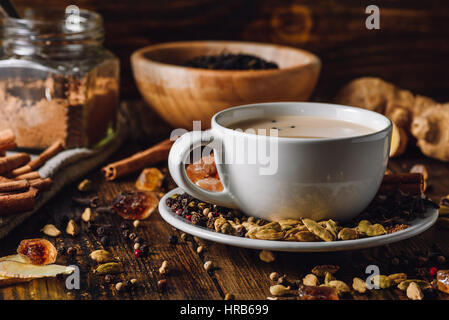 Chai masala dans la tasse blanche avec différentes épices sur table en bois Banque D'Images