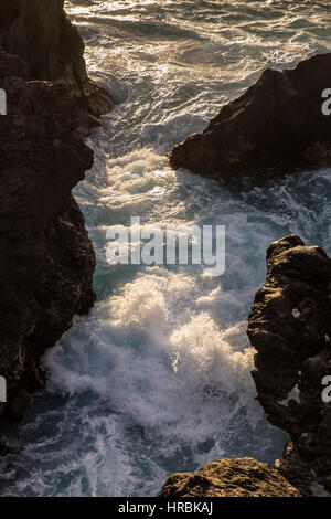 Se précipitant dans la mer entre les rochers à la fin de lumière du soir sur la côte ouest de Tenerife, Canaries, Espagne Banque D'Images