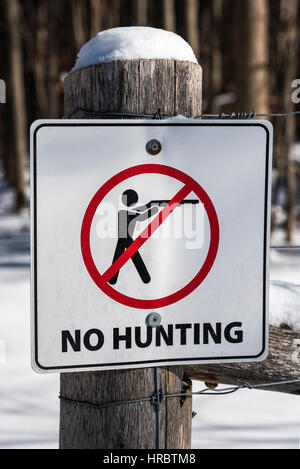 Pas de chasse d'un signe sur un poteau de bois avec de la neige sur l'entrée d'un parc de l'Ontario au Canada. Banque D'Images
