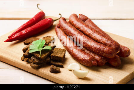 Salami fumé saucisse avec l'ail, les croûtons et les piments on cutting board Banque D'Images