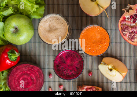 Trois verres de jus frais. La betterave, carotte et jus de pomme sur fond de bois gris. Banque D'Images