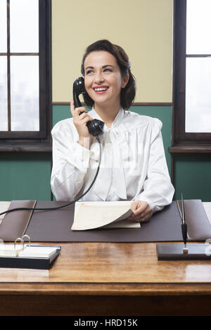 Smiling vintage réceptionniste travaillant au bureau et smiling Banque D'Images