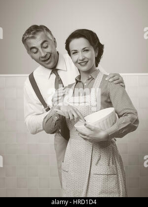 Vintage couple amoureux à la maison, elle porte un tablier de cuisine et Banque D'Images