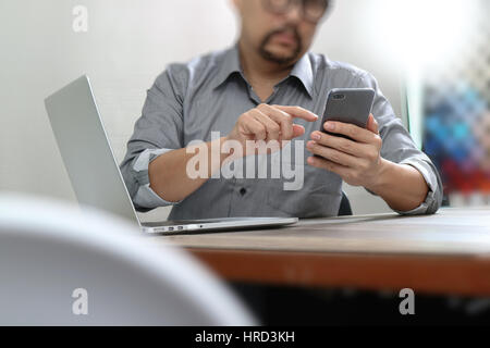 Businessman hand en utilisant les paiements mobiles,vente en ligne,crayon omni channel,ordinateur portable sur un bureau en bois in modern office Banque D'Images