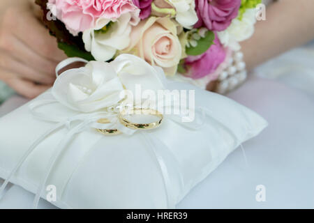 Coussin blanc avec deux anneaux de mariage d'or Banque D'Images