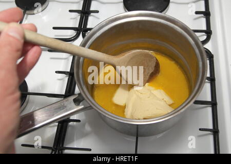 Faire fondre le beurre dans une casserole avec une cuillère en bois sur la table de cuisson, prêt à cuire crêpes Banque D'Images