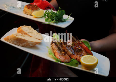 Crevettes fraîchement cuit sur un lit de laitue avec du pain frais est servi à une table de restaurant. Banque D'Images