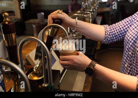 Barmaid pulling a pint of beer, remoulages Doombar, dans un pub. Banque D'Images