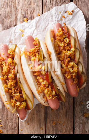 Alimentaire danois : hot dog avec oignons croustillants et concombres close-up sur la table. vertical Vue de dessus Banque D'Images