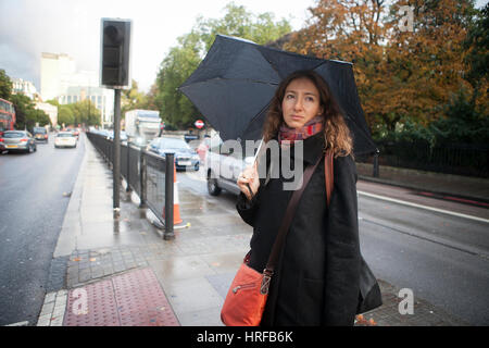 Londres, Angleterre - le 12 octobre 2016 femme seule avec umbreall traverser la route Banque D'Images