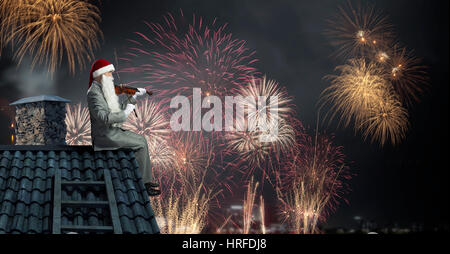 Le Père Noël sur le toit de maison à jouer du violon. Technique mixte Banque D'Images