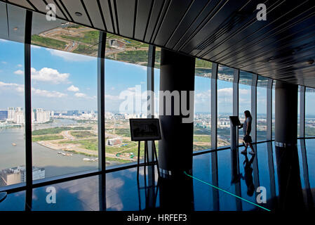 Un touriste à la recherche de la vue depuis le Saigon Skydeck dans la Bitexco Financial Tower sur une journée ensoleillée avec ciel bleu. Banque D'Images