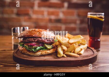 Fresh burger, frites, salade et soda sur table en bois. Banque D'Images