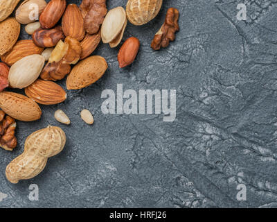 Arrière-plan de mélanges de Noix - noisettes, noix, amandes - sur fond de béton foncé avec copie espace. Vue supérieure ou télévision lay Banque D'Images