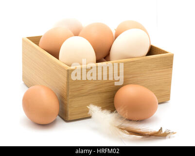 Boîte en bois rempli d'oeufs de poule brun et blanc isolé sur blanc. Banque D'Images