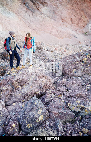 Plan large portrait vertical de petite jeune couple, homme et femme, portant de gros sacs à dos touristique et debout sur la colline parlementaire tenant la main contre backg Banque D'Images