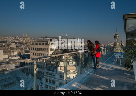 2 Filles profiter de la vue imprenable sur les toits de Paris sur un jour d'hiver ensoleillé avec Sacré-Cœur à la distance. Banque D'Images