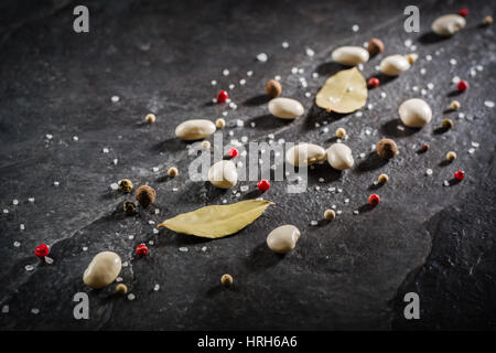 Haricots blancs et d'épices sont répartis au hasard sur une table en pierre noire de l'ardoise. L'espace pour le texte. Banque D'Images