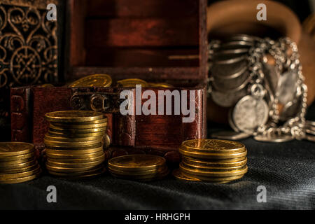 Coffre à Trésor, pieu et pilier de pièces en céramique, un bol rempli de pièces de monnaie et bijoux lampe bougie dans l'obscurité Banque D'Images