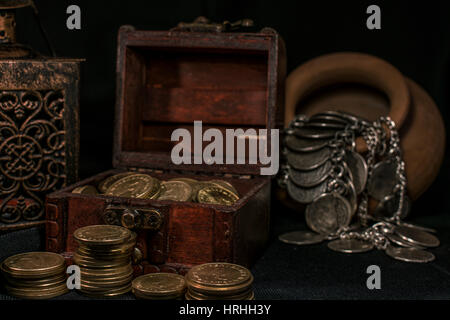 Coffre à Trésor, pieu et pilier de pièces en céramique, un bol rempli de pièces de monnaie et bijoux lampe bougie dans l'obscurité Banque D'Images