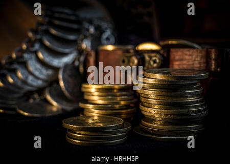 Coffre de trésor, pile et pilier de la monnaie, et un bol en céramique rempli de pièces de bijoux dans l'obscurité Banque D'Images