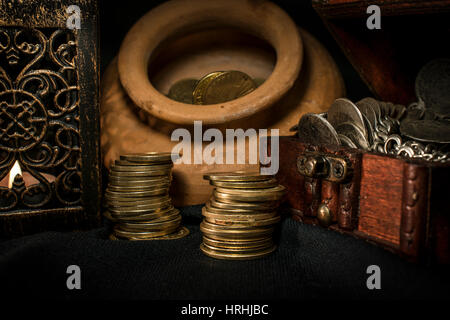 Coffre à Trésor, pieu et pilier de pièces en céramique, un bol rempli de pièces de monnaie et bijoux lampe bougie dans l'obscurité Banque D'Images