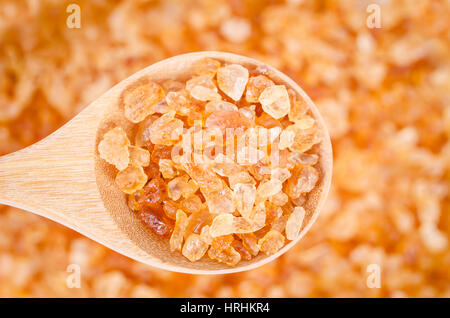 Cristaux de sucre sain en cuillère en bois sur fond de sucre. Banque D'Images