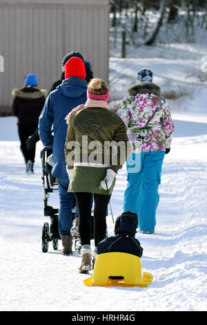 Woman pulling petit enfant sur une luge jaune. Banque D'Images